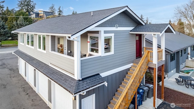 view of side of home with roof with shingles