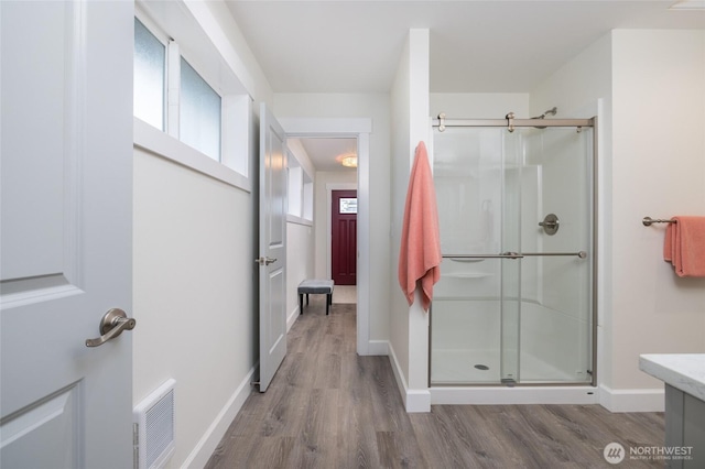 bathroom with a stall shower, visible vents, and wood finished floors