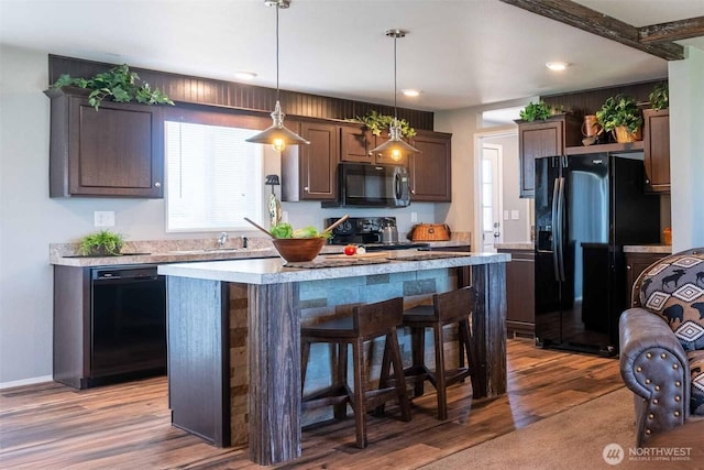 kitchen featuring dark brown cabinetry, black appliances, a kitchen island, and decorative light fixtures