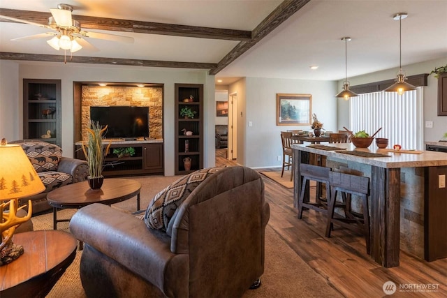 living room featuring beam ceiling, ceiling fan, dark hardwood / wood-style floors, and built in shelves