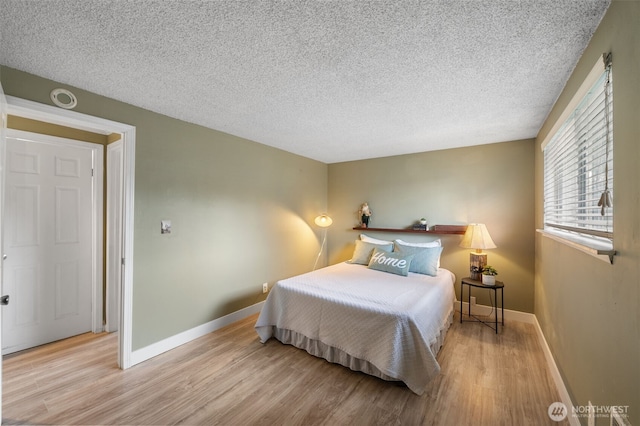 bedroom with light hardwood / wood-style floors and a textured ceiling