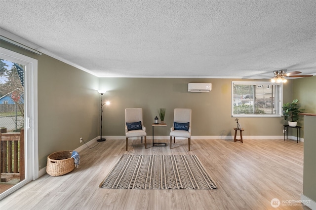 sitting room featuring light hardwood / wood-style flooring, ornamental molding, an AC wall unit, and a textured ceiling