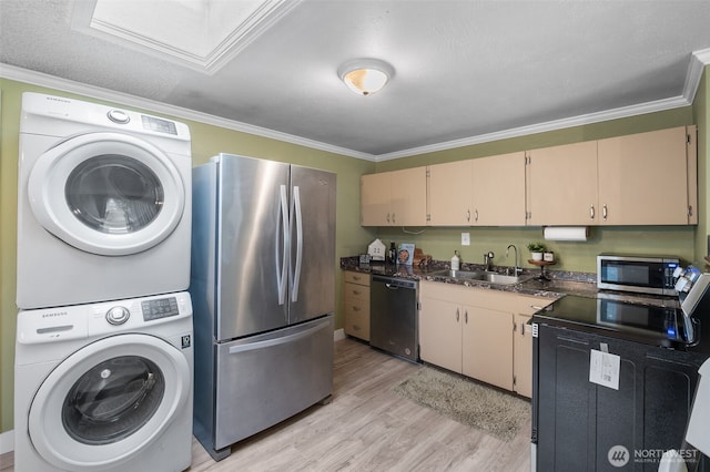 kitchen with sink, crown molding, stacked washing maching and dryer, appliances with stainless steel finishes, and light wood-type flooring