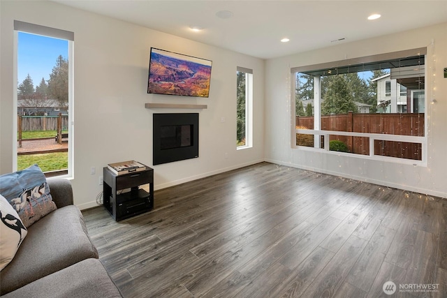 living room featuring a glass covered fireplace, recessed lighting, dark wood finished floors, and baseboards