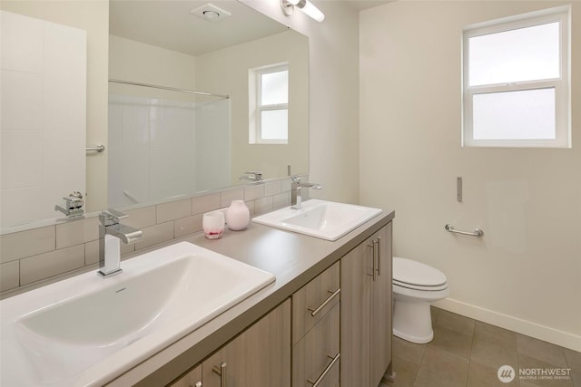 full bath with backsplash, a sink, toilet, and baseboards