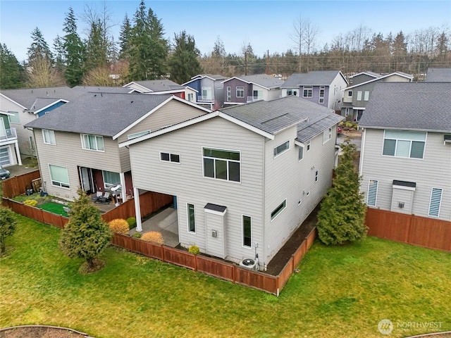 back of house with a lawn, a fenced backyard, and a residential view