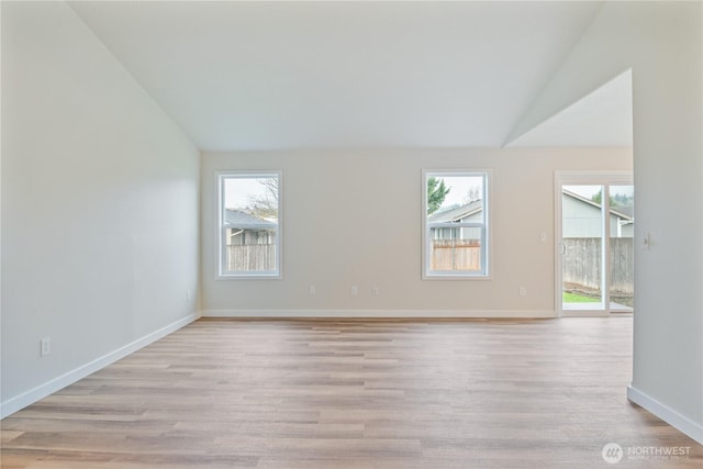 spare room with a wealth of natural light, baseboards, lofted ceiling, and light wood finished floors