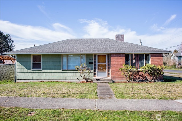 single story home featuring a shingled roof, brick siding, a chimney, and a front lawn