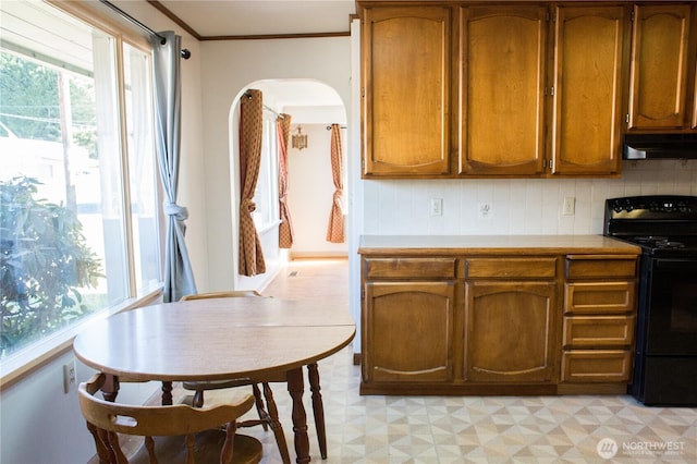 kitchen featuring light floors, black range with electric cooktop, under cabinet range hood, and light countertops