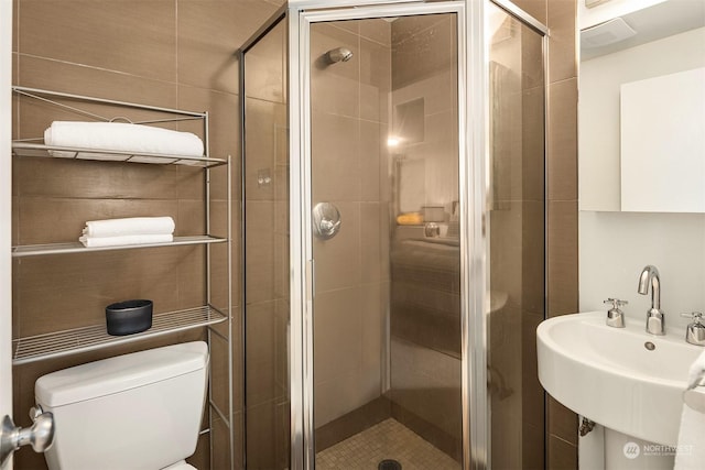 bathroom featuring an enclosed shower, sink, and toilet