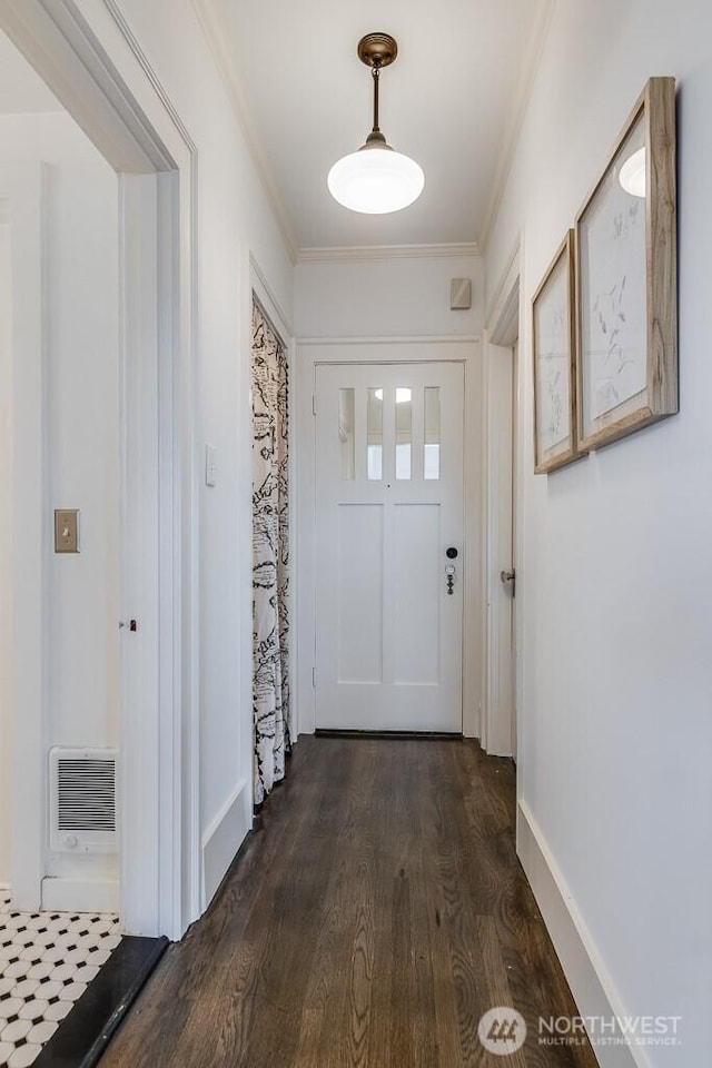 doorway to outside featuring dark wood-style flooring, visible vents, crown molding, and baseboards