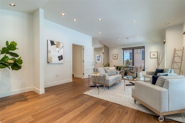 living room featuring light wood-type flooring, baseboards, and recessed lighting