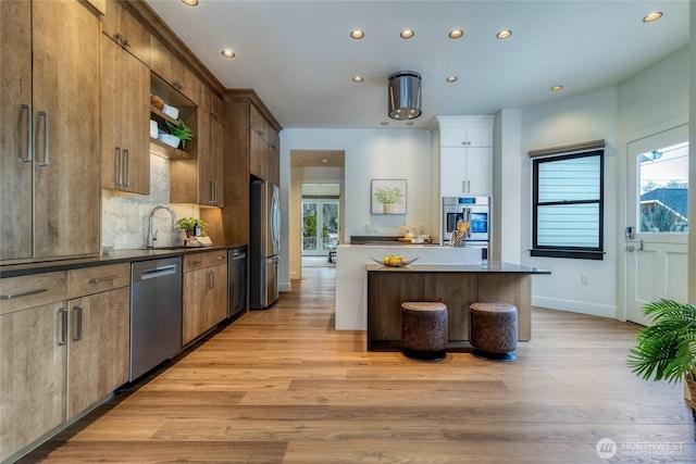 kitchen with plenty of natural light, stainless steel appliances, dark countertops, and a sink