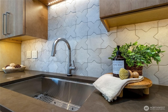 room details featuring tasteful backsplash, dark countertops, and a sink