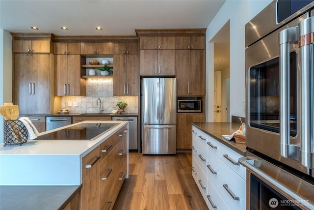 kitchen featuring stainless steel appliances, a sink, white cabinets, open shelves, and dark countertops