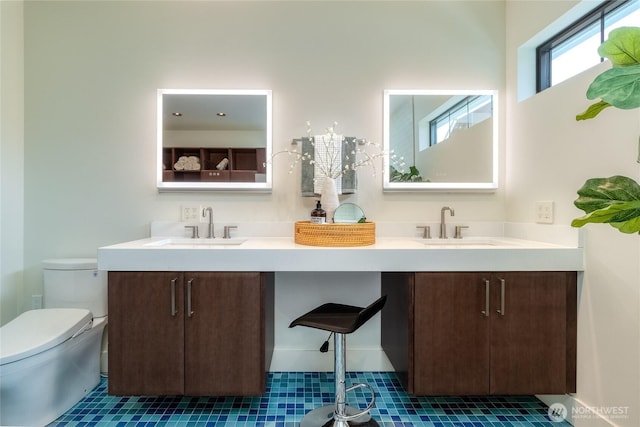 bathroom with tile patterned floors, a sink, toilet, and double vanity