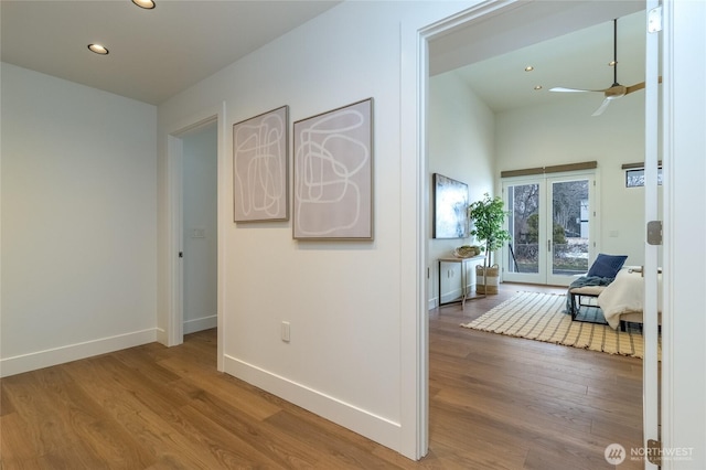 corridor featuring baseboards, french doors, wood finished floors, and recessed lighting