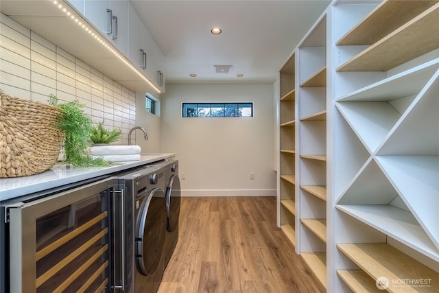 interior space featuring baseboards, wine cooler, washing machine and clothes dryer, light wood-style floors, and recessed lighting