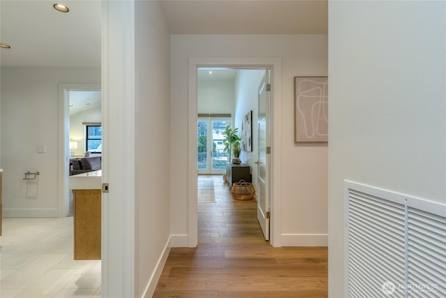 hallway featuring light wood-style floors, baseboards, and recessed lighting