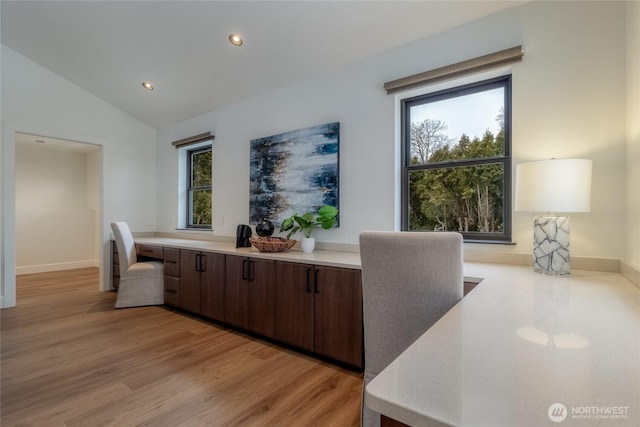 interior space featuring light wood finished floors, baseboards, built in study area, vaulted ceiling, and recessed lighting