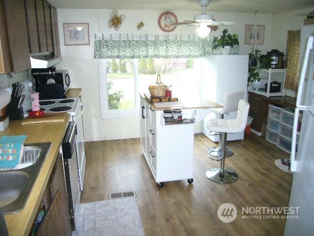 kitchen featuring sink, dark hardwood / wood-style floors, white fridge, ceiling fan, and exhaust hood