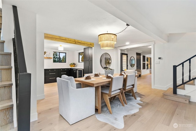 dining space featuring light wood-type flooring and beam ceiling