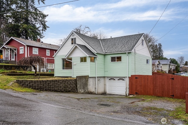 view of front of home featuring roof with shingles, an attached garage, and fence