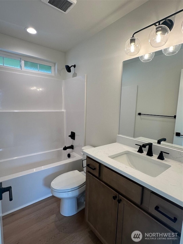 full bathroom with visible vents, toilet, wood finished floors, tub / shower combination, and vanity