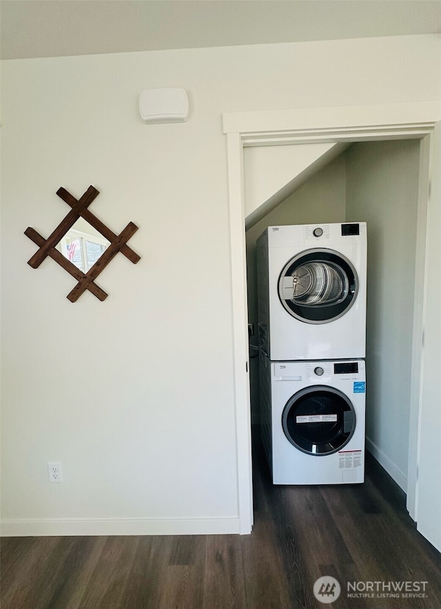 laundry area featuring laundry area, dark wood finished floors, stacked washer and clothes dryer, and baseboards