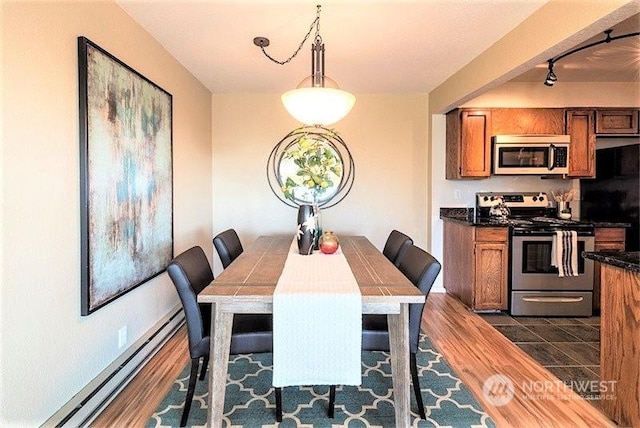 dining area featuring dark wood-type flooring and a baseboard heating unit