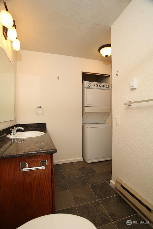 bathroom featuring vanity, tile patterned flooring, a baseboard radiator, and stacked washer / dryer