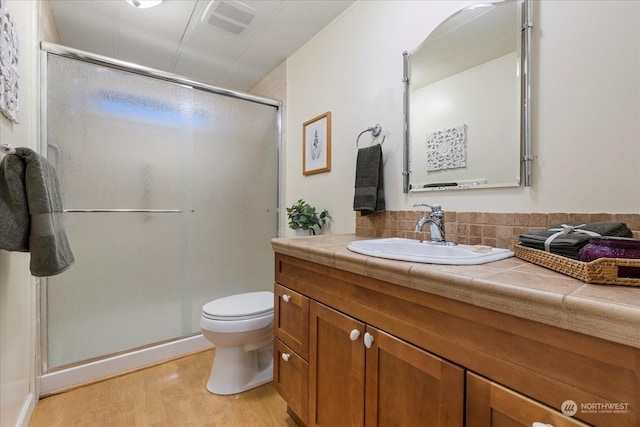 bathroom featuring hardwood / wood-style flooring, vanity, an enclosed shower, and toilet