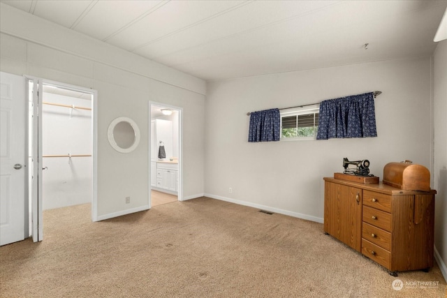 bedroom with a walk in closet, light colored carpet, a closet, and ensuite bathroom