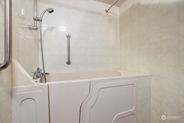 bathroom with tiled shower and tile walls