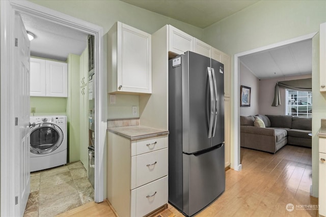 kitchen with white cabinets, washer / dryer, stainless steel fridge, and light hardwood / wood-style flooring