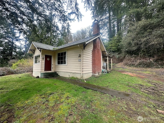 view of front of property featuring entry steps, a front lawn, and a chimney