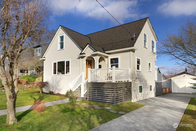 view of front of home with a shed, a garage, a front lawn, and covered porch