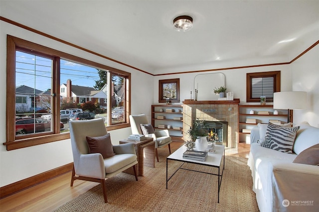 living room featuring a tiled fireplace, crown molding, and hardwood / wood-style floors