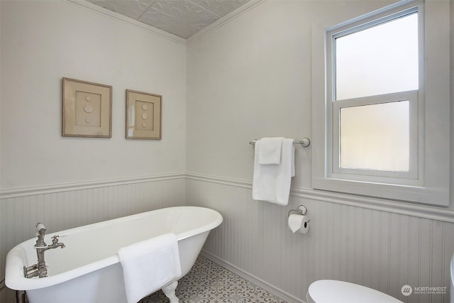 bathroom with ornamental molding, a tub, and toilet