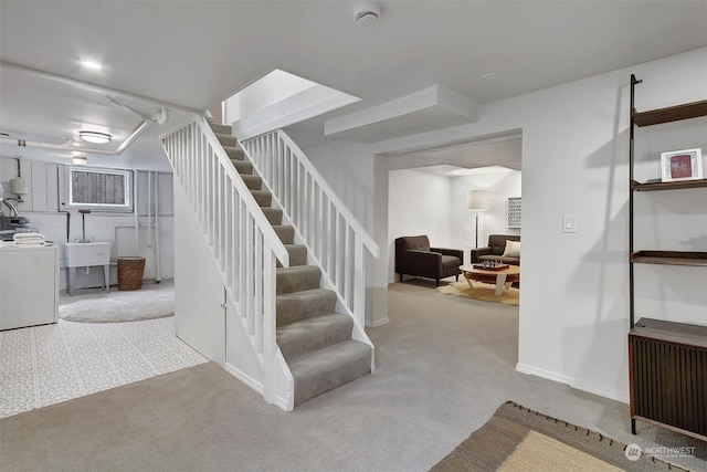 staircase with washer / clothes dryer, radiator, sink, and carpet