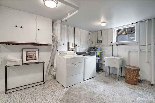 laundry room featuring strapped water heater, sink, cabinets, and washer and dryer