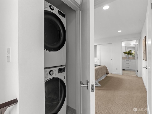 laundry area featuring stacked washer and clothes dryer and light carpet