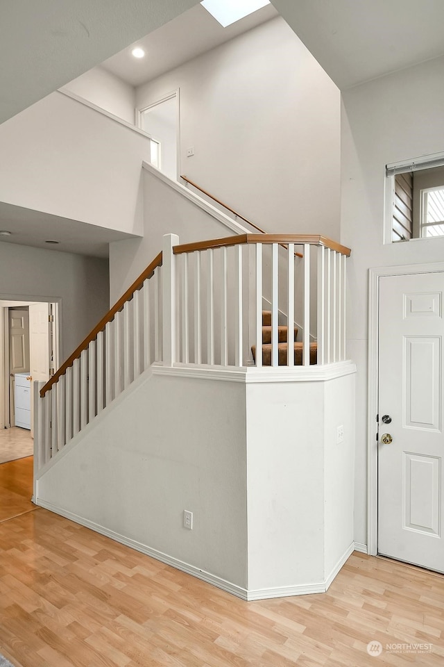 stairway with recessed lighting, a high ceiling, and wood finished floors