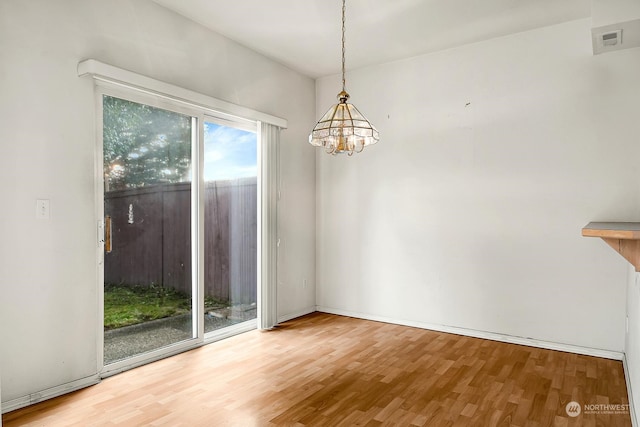 unfurnished room featuring wood finished floors and a notable chandelier