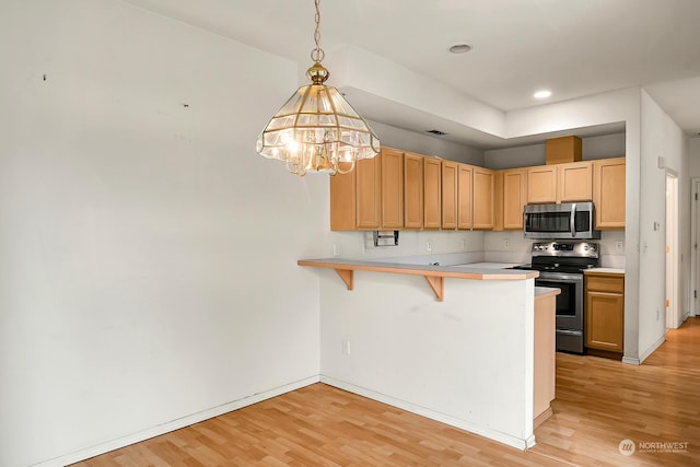 kitchen with a peninsula, stainless steel appliances, light countertops, light brown cabinetry, and pendant lighting