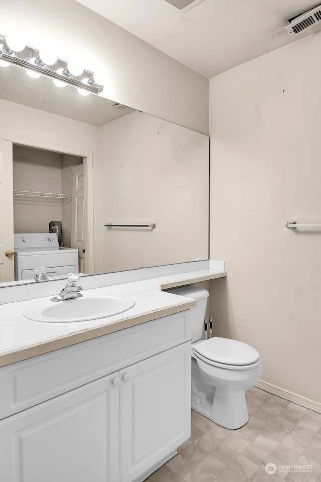 half bathroom with visible vents, toilet, vanity, washer / dryer, and tile patterned floors