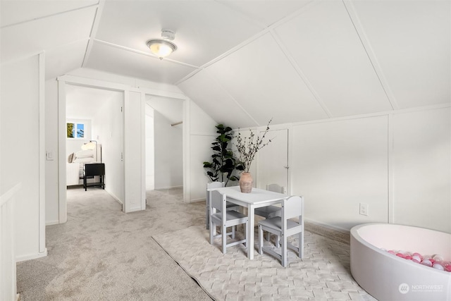 dining space featuring vaulted ceiling and light colored carpet