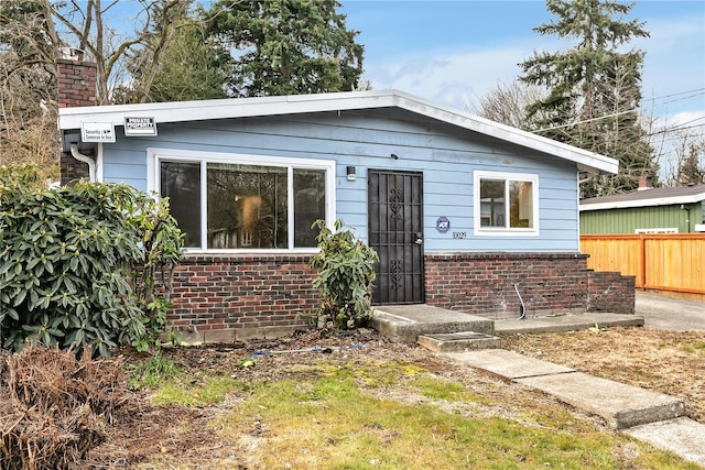 bungalow featuring fence and brick siding