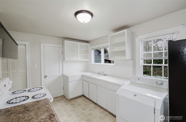 kitchen featuring sink, black fridge, washer / dryer, white range with electric cooktop, and white cabinets