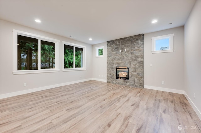 unfurnished living room featuring a tile fireplace and light wood-type flooring